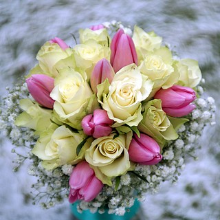 Wiązanka ślubna na tle śniegu. Białe róże i różowe tulipany